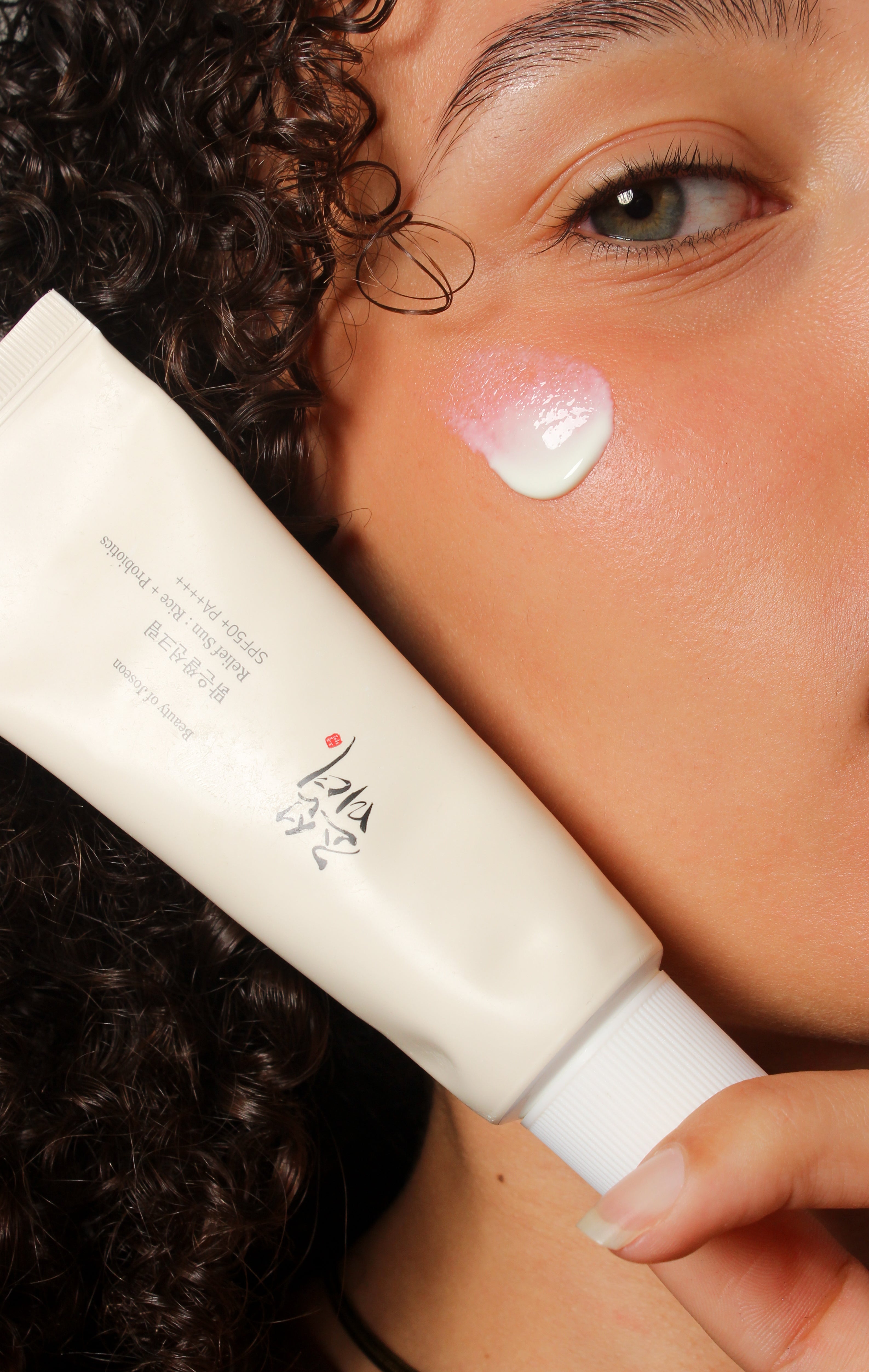 Mannequin avec crème solaire appliquée sur le visage tenant le flacon Beauty of Joseon