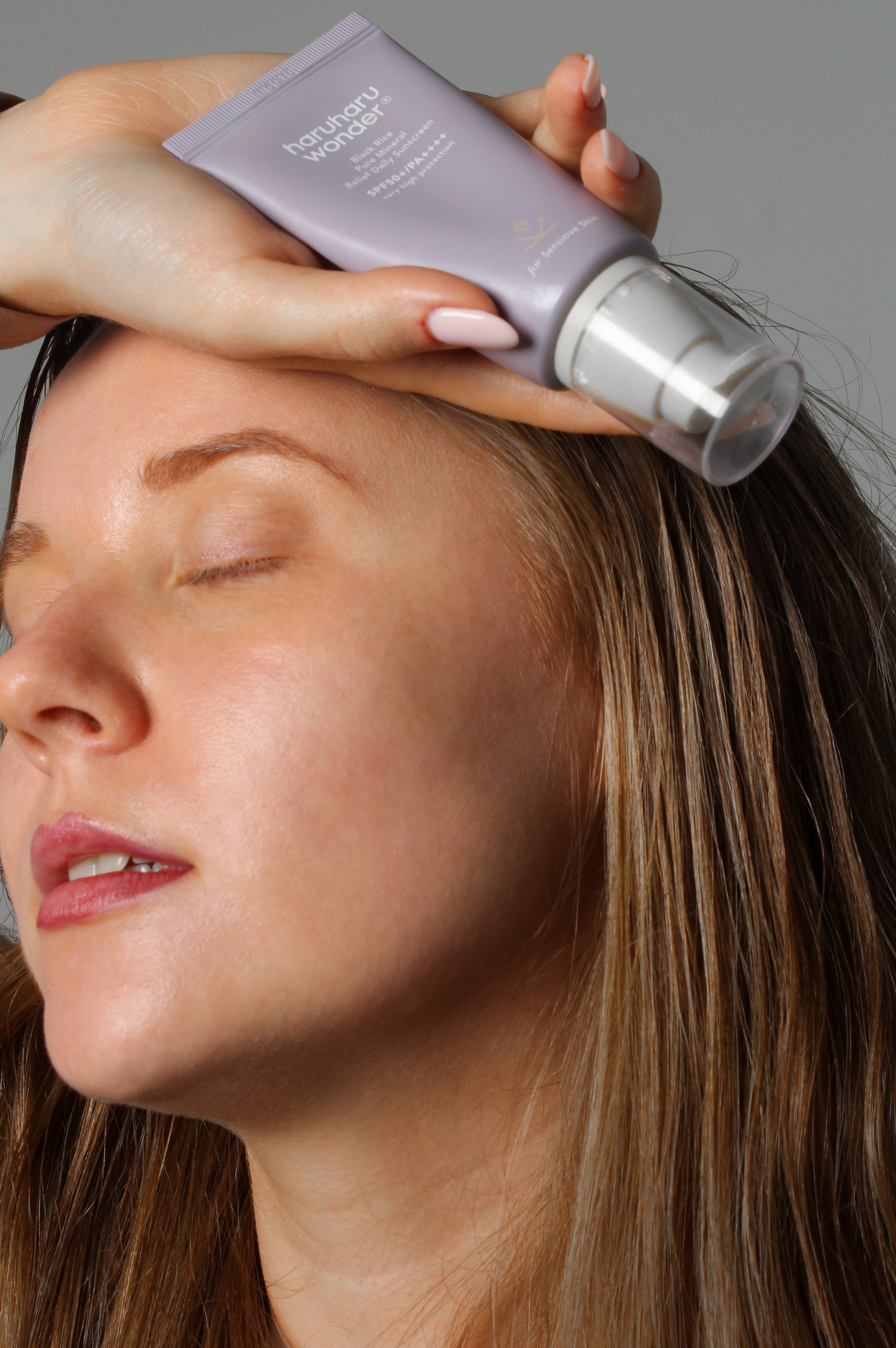 Mannequin tenant la crème solaire pure mineral relief riz noir Haruharu Wonder, sourire naturel