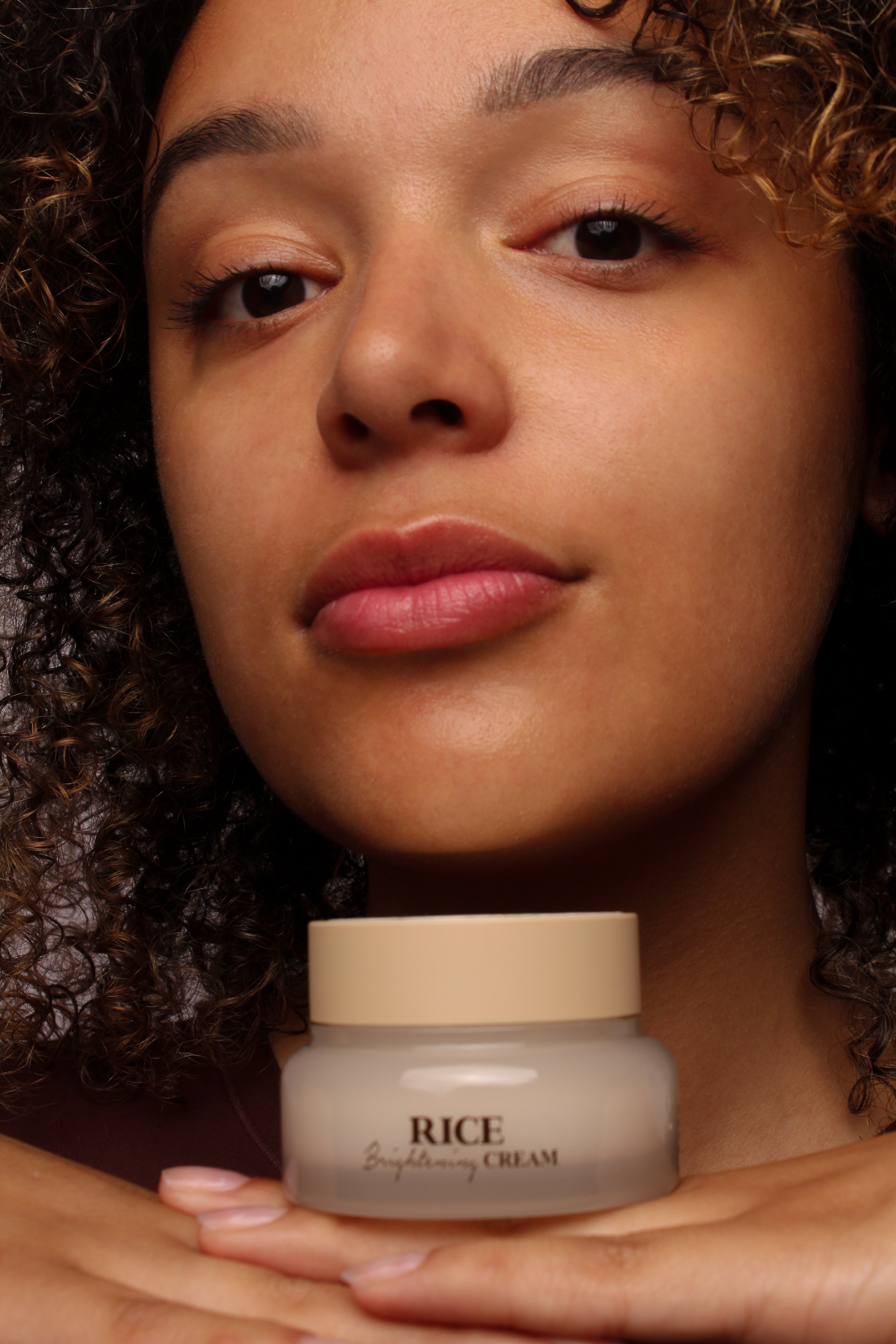 Mannequin tenant la crème éclaircissante au riz Skinfood, sourire naturel