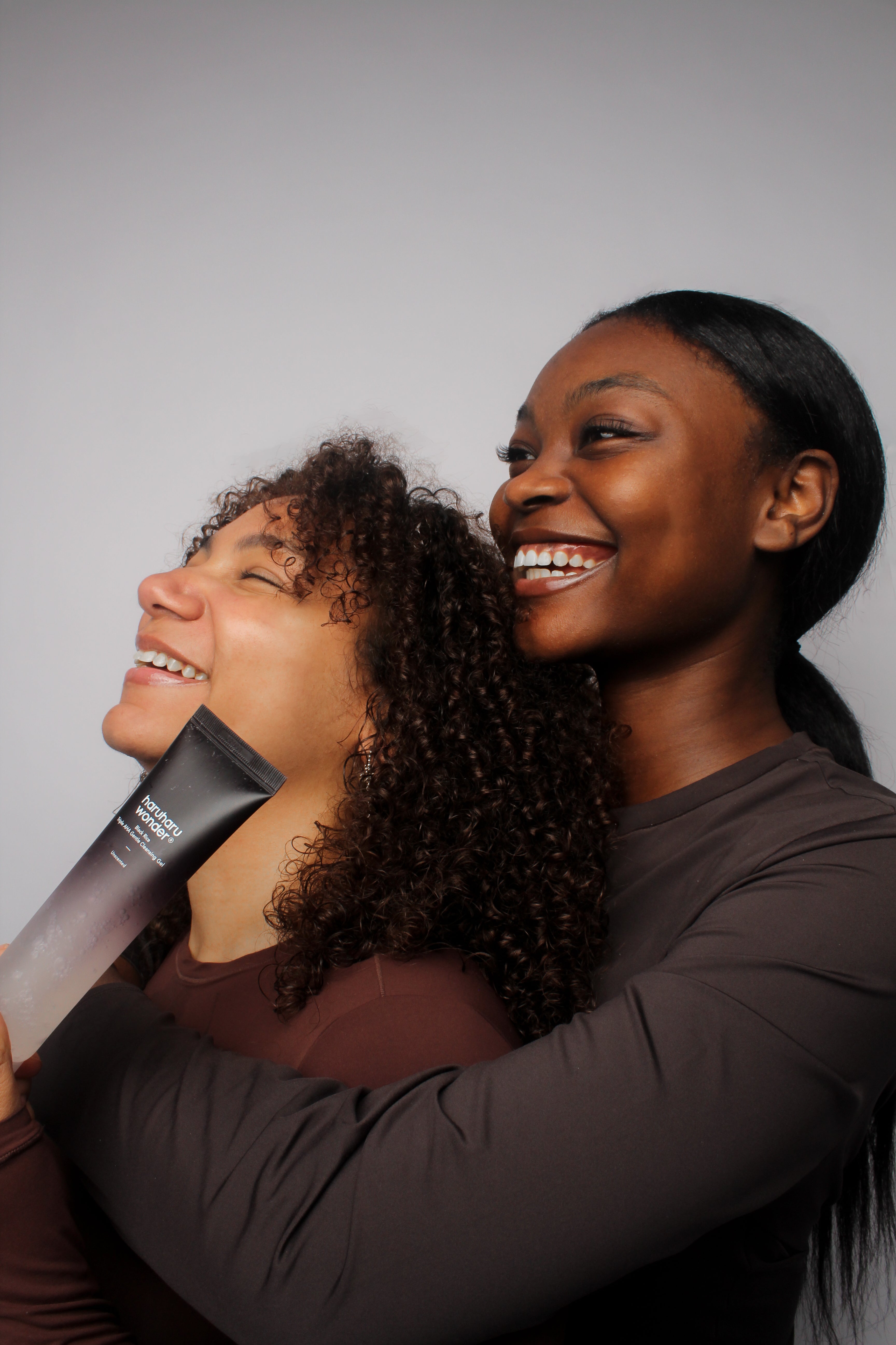 Deux mannequins souriants tenant le gel nettoyant doux triple AHA au riz noir Haruharu Wonder