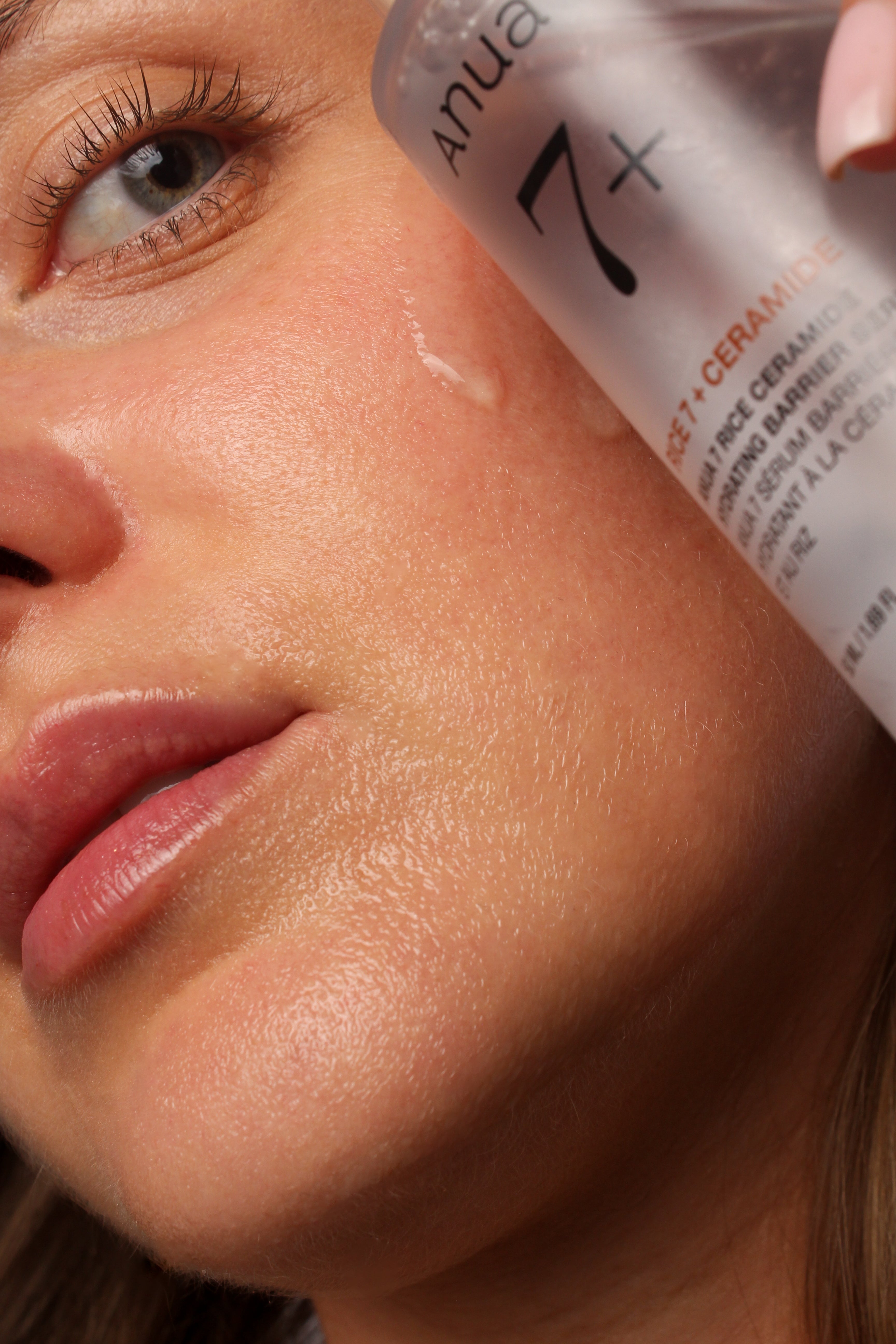 Mannequin avec sérum barrière hydratant aux céramides de riz 7 Anua appliqué sur le visage, tenant le flacon dans la main