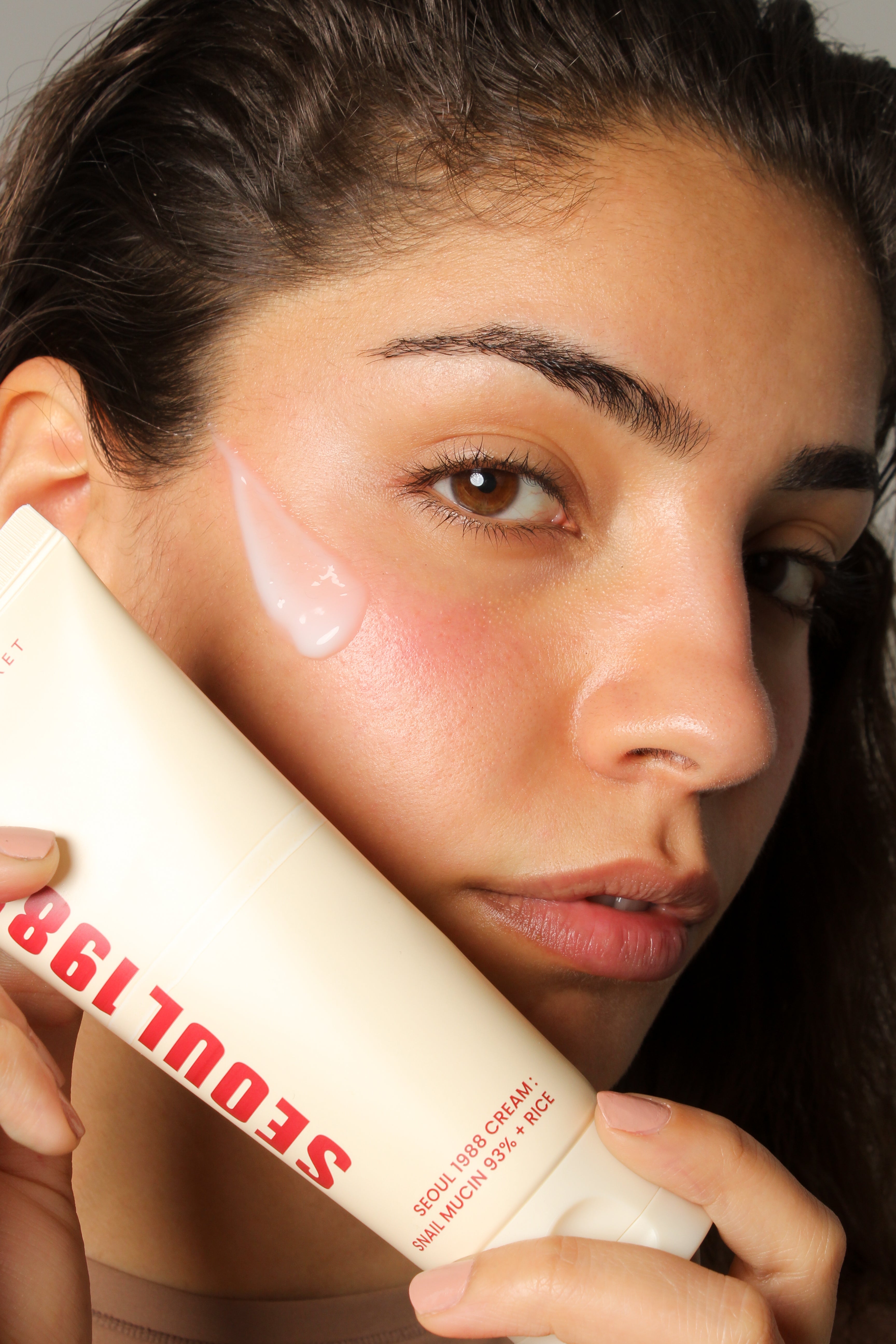Mannequin tenant la crème mucine d'escargot 93% + riz Seoul 1988, sourire naturel