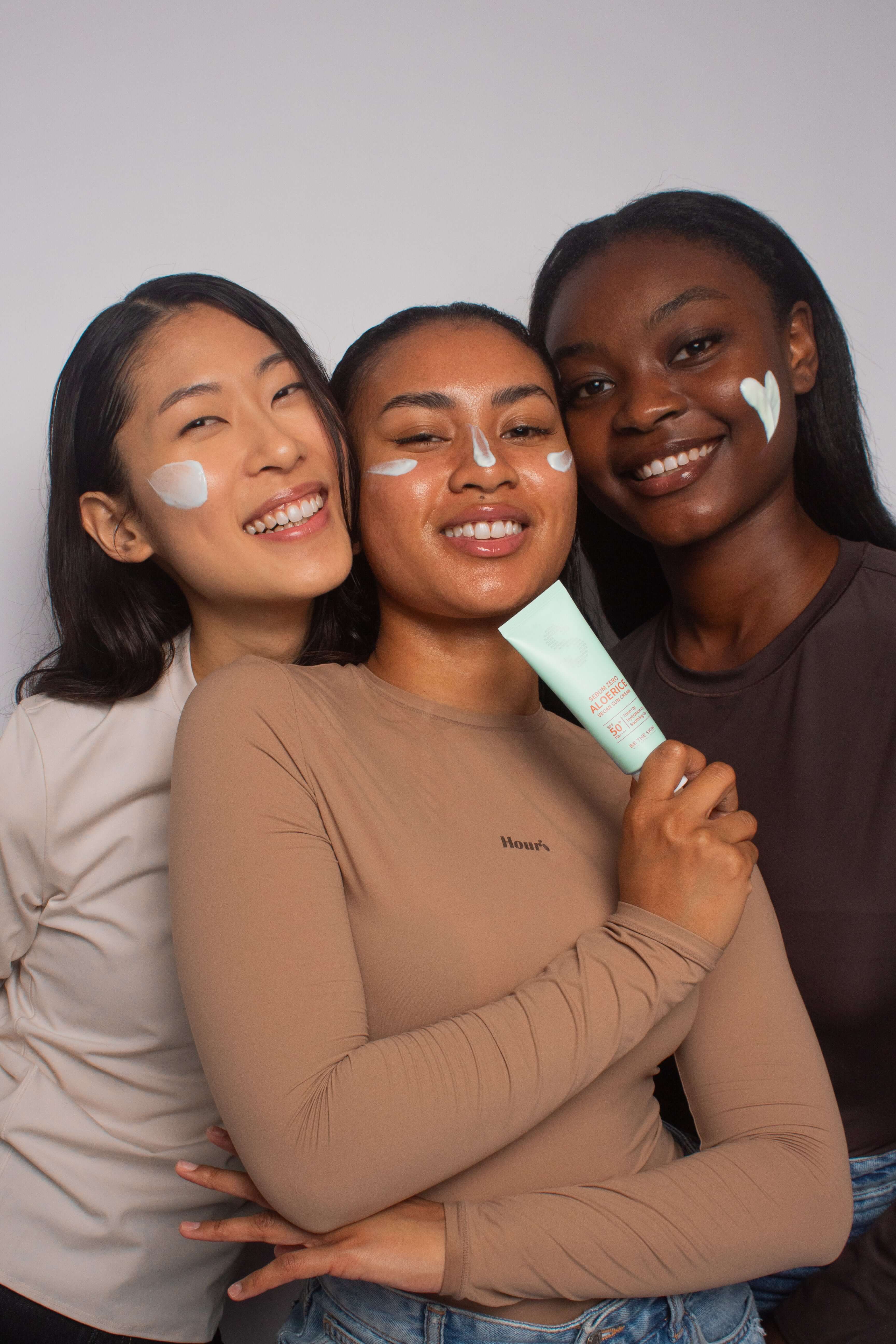 Groupe de mannequins de différentes carnations utilisant la crème solaire Be The Skin au riz