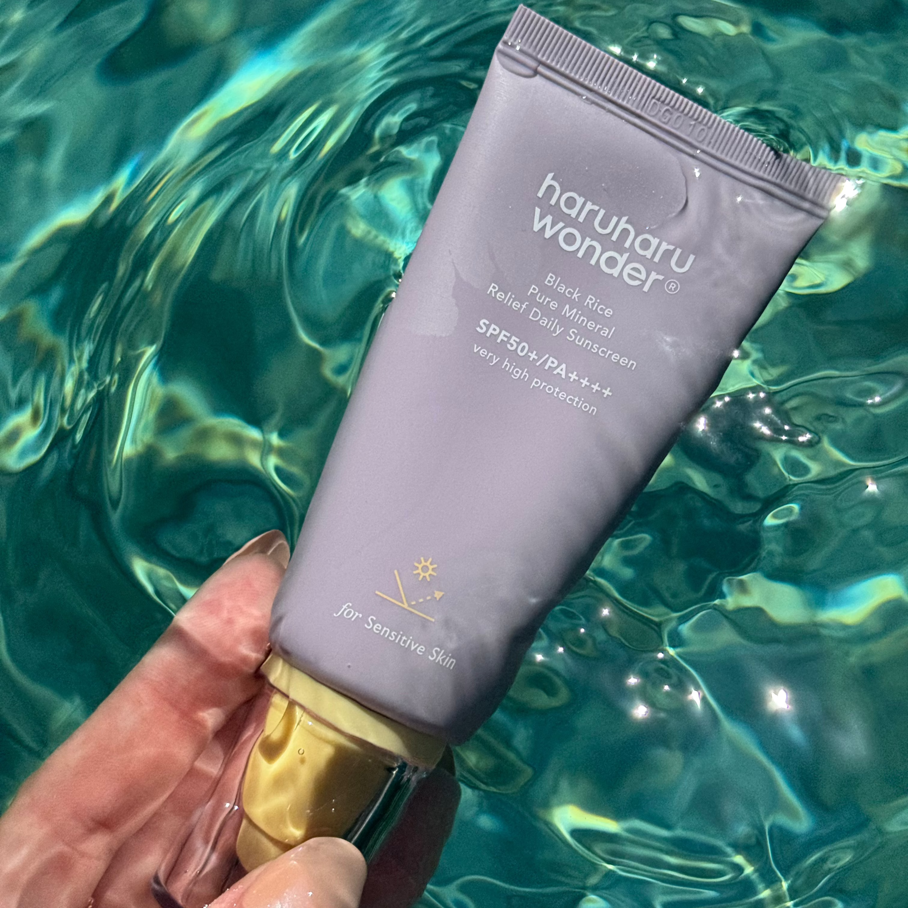 Tube de crème solaire pure mineral relief riz noir Haruharu Wonder posé au bord de la piscine