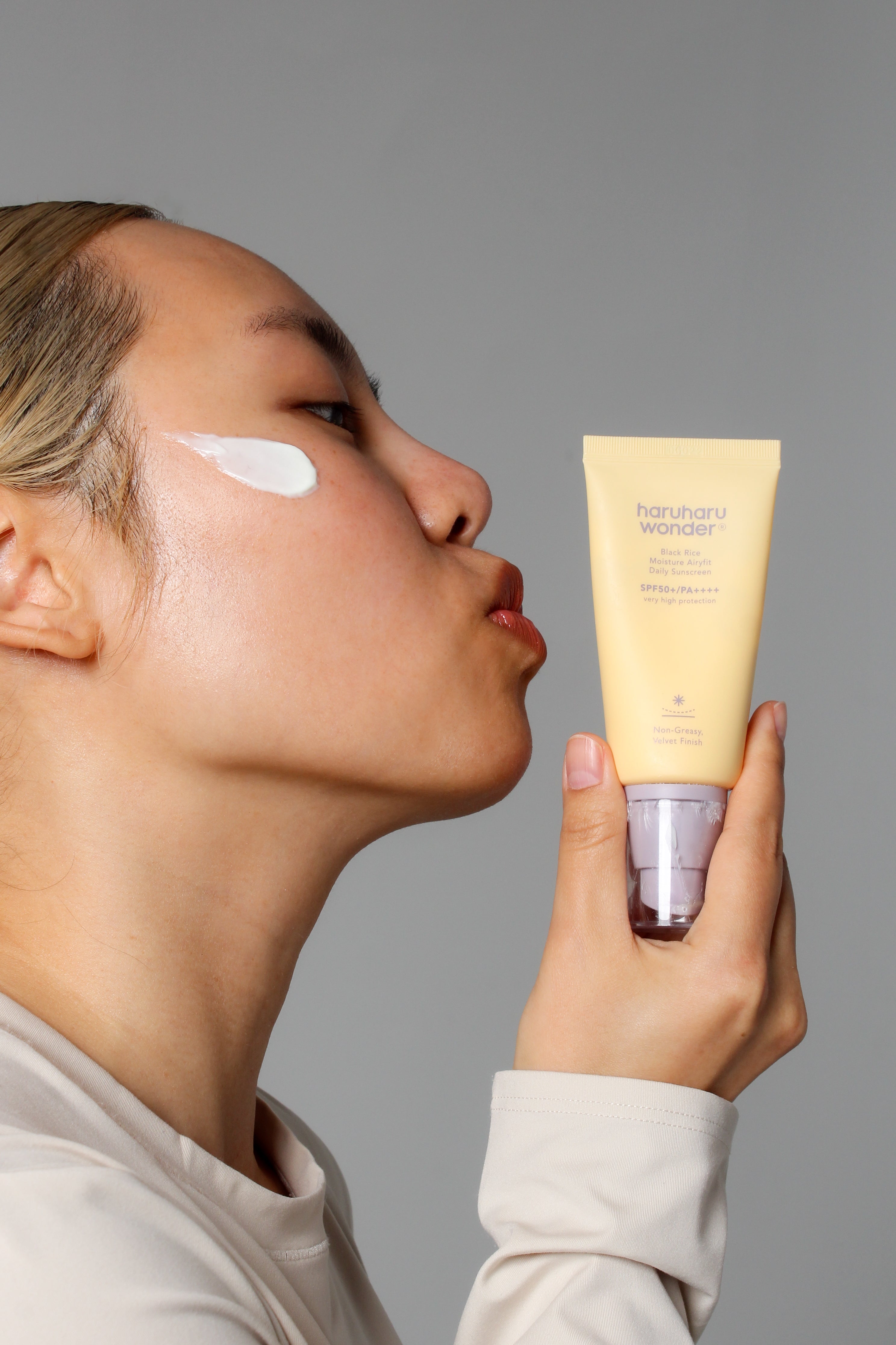 Mannequin embrassant la crème solaire Airyfit riz noir SPF50+ Haruharu Wonder face à elle