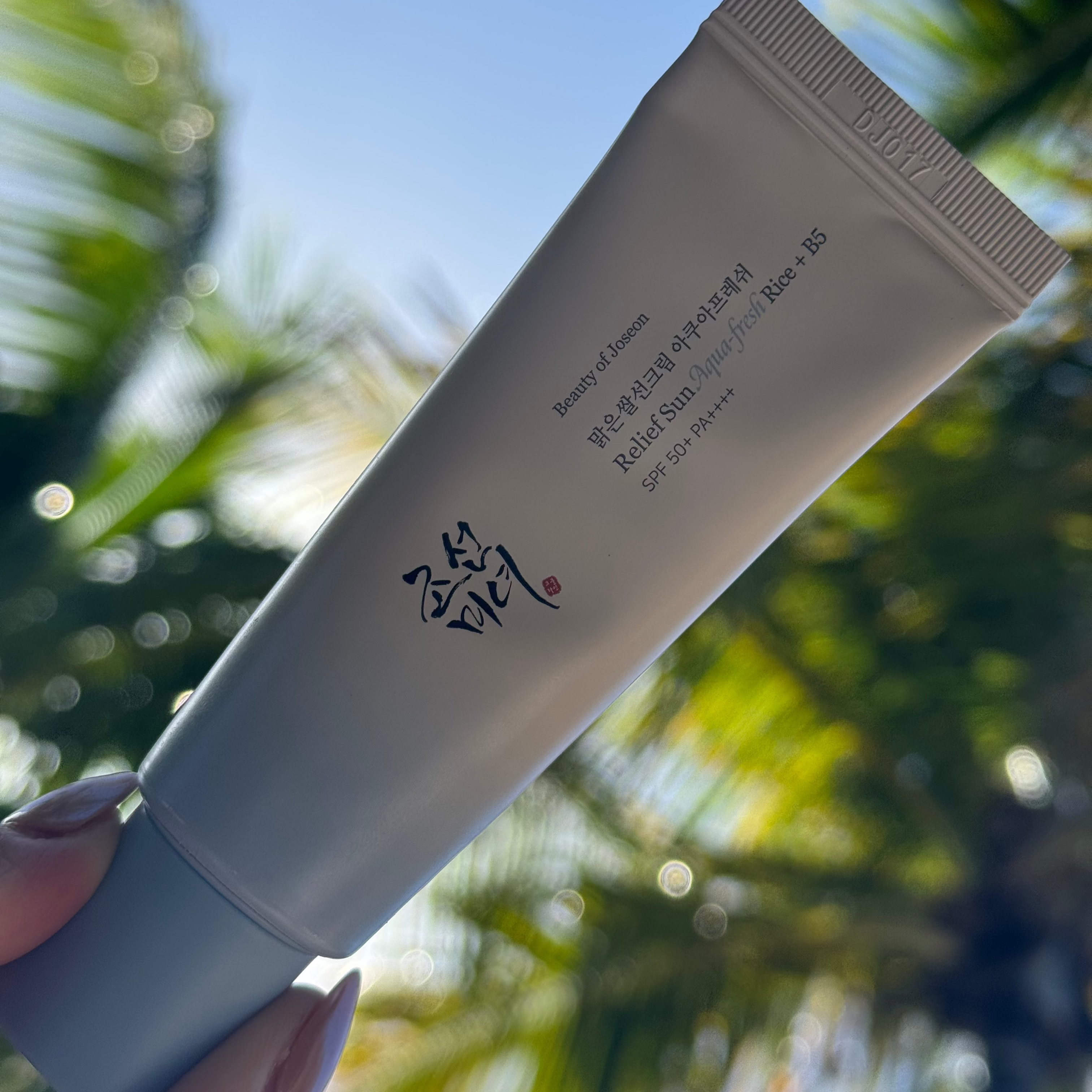 Tube de crème solaire Aquafresh Riz & B5 Beauty of Joseon avec fond plage et palmiers